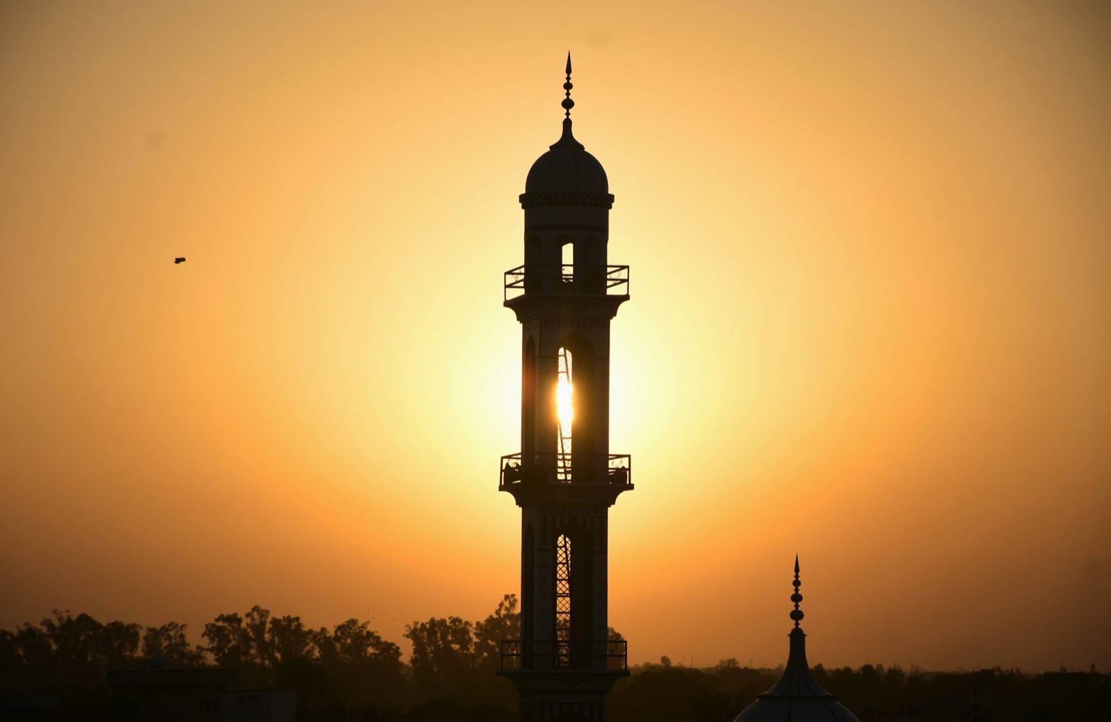 A quiet mosque minaret against soft golden dawn light