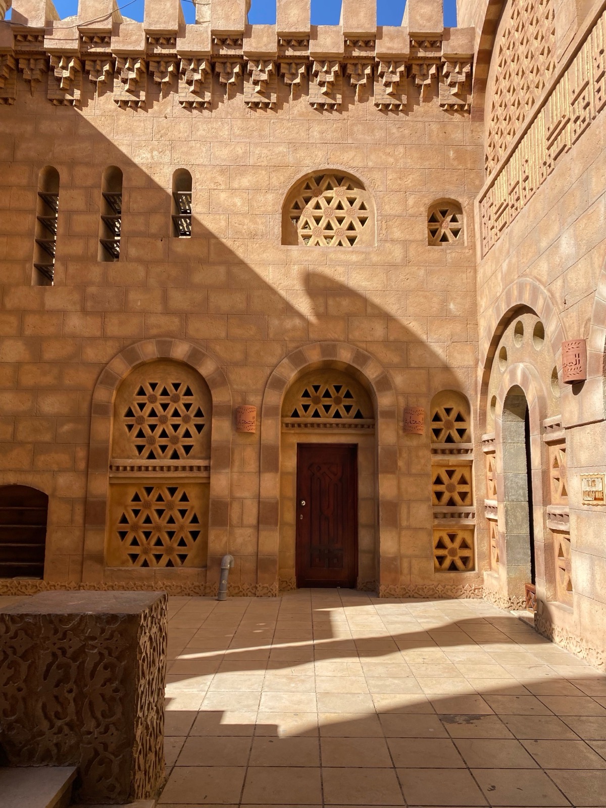 A sunlit courtyard framed by warm mud-brick arches